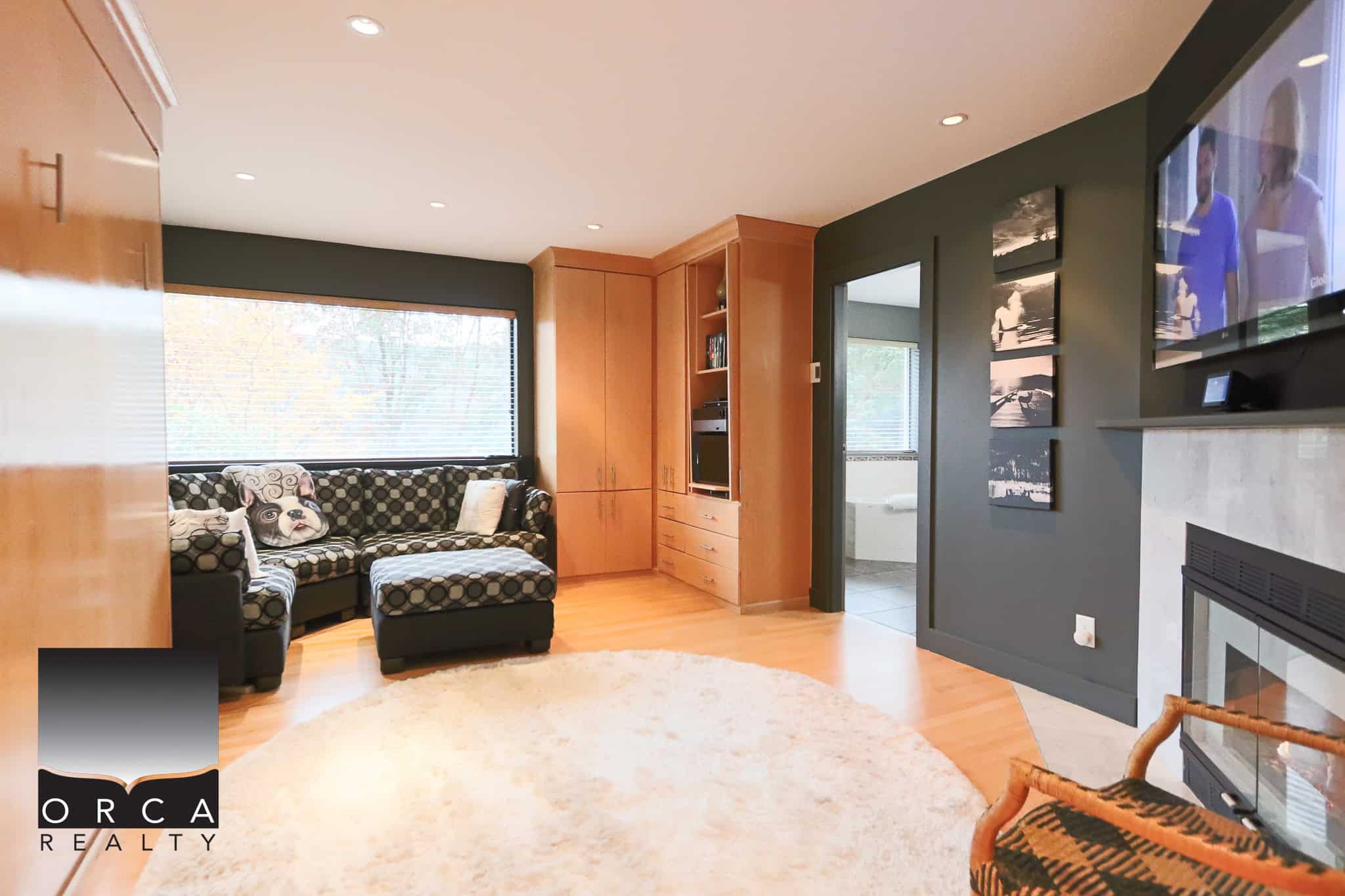 Bright living room with large window, modern decor, hardwood floors, cozy fireplace, and contemporary furniture, showcasing Vancouver-area real estate by Orca Realty Inc.