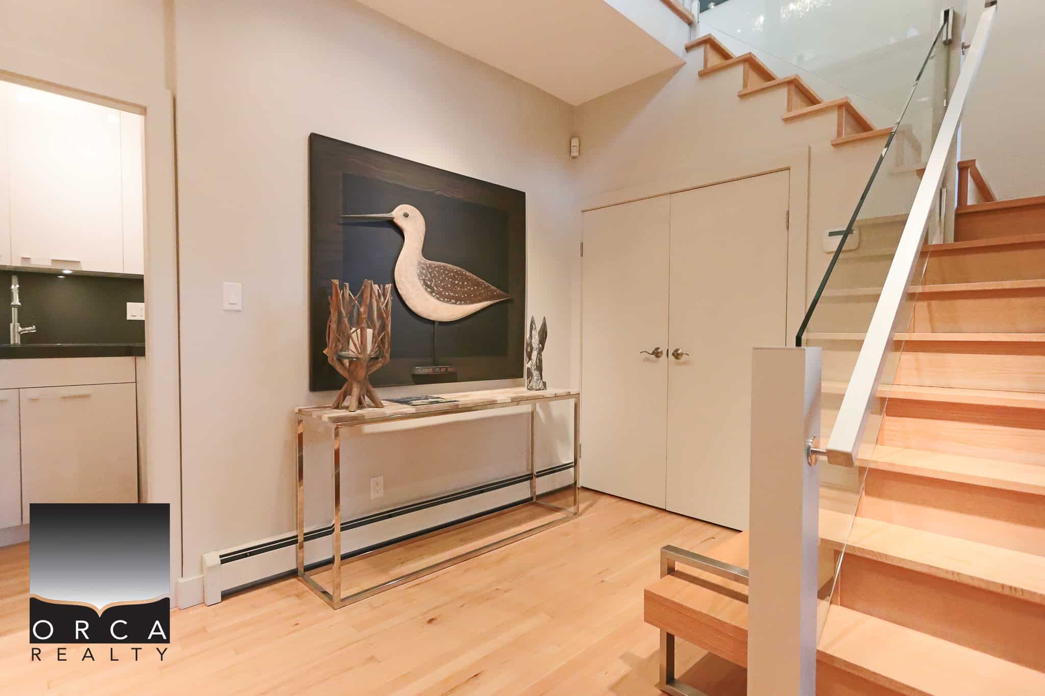Contemporary interior of a modern home with wooden stairs, minimalist decor, and coastal-inspired artwork, highlighting luxury real estate in Vancouver and BC.