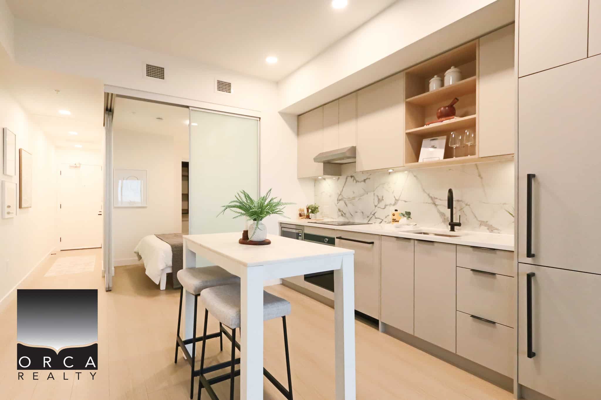 Sleek modern kitchen in a stylish condo with white cabinetry, marble backsplash, and minimalist decor, ideal for contemporary living and property investment.