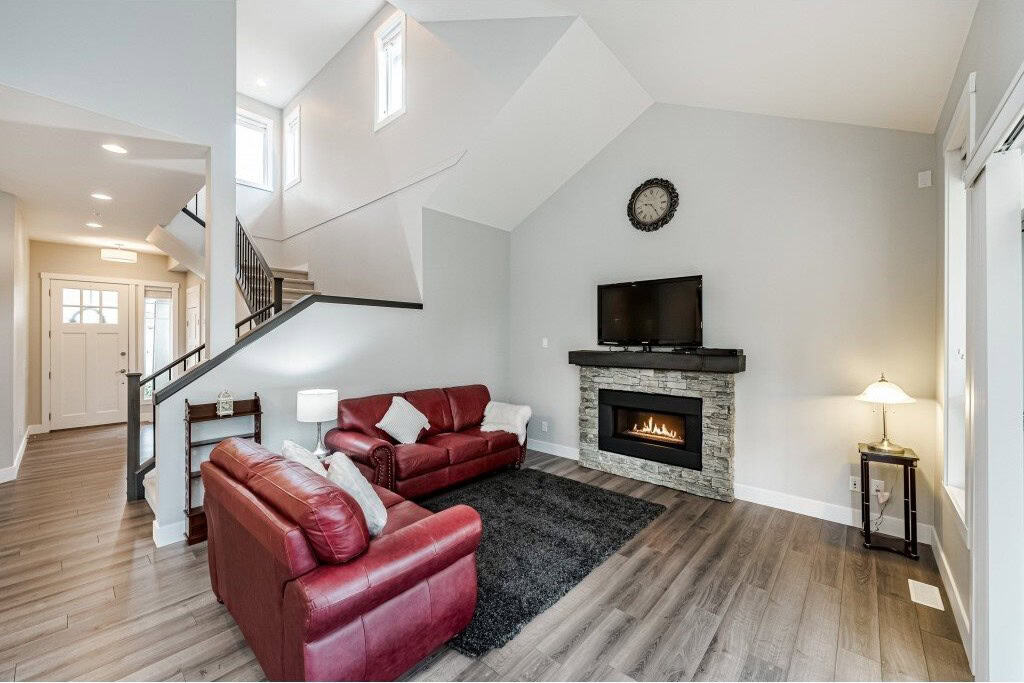 Cozy living room with modern fireplace, grey walls, and red leather sofas in a contemporary home. Ideal for relaxing and entertaining, showcasing quality interior design.