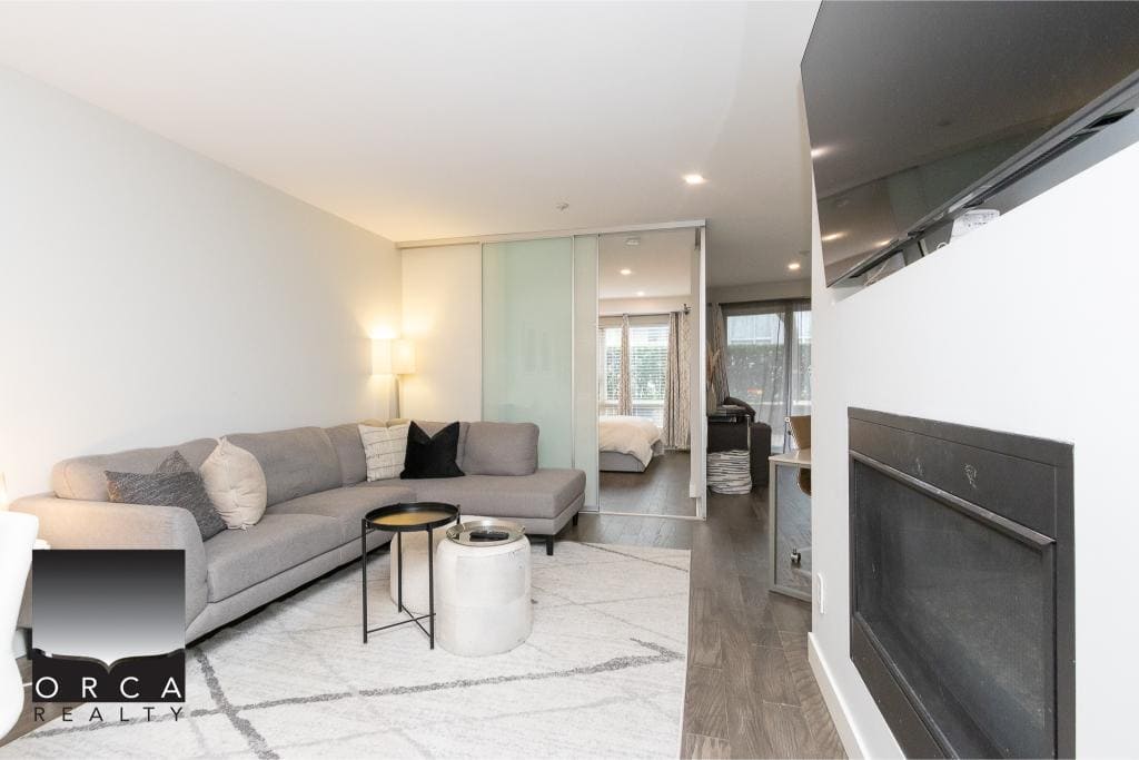 Modern living room with a cozy grey sectional, stylish decor, and an open-concept layout showcasing contemporary interior design in a Vancouver-area condo.