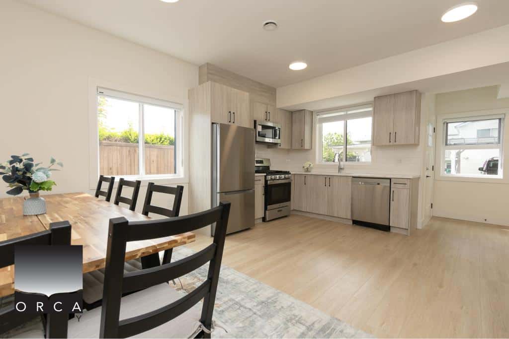 Modern kitchen with stainless steel appliances and light wood cabinetry in a bright, open-concept living space.