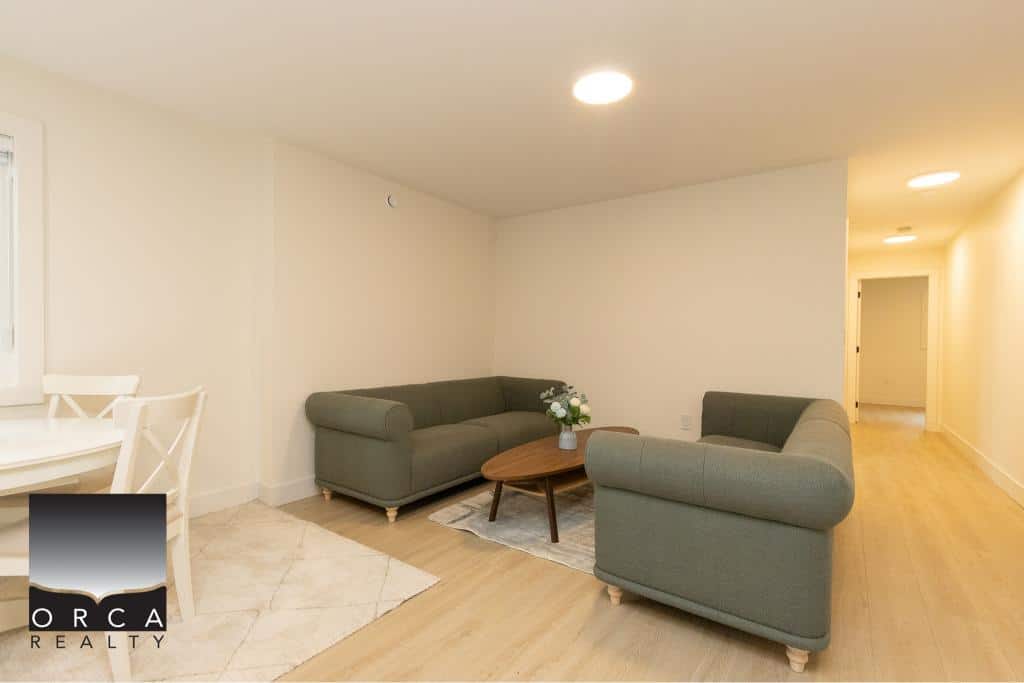 Modern living room interior with neutral tones, comfortable sofas, and minimalist decor in a real estate property managed by Orca Realty Inc., Vancouver Island.