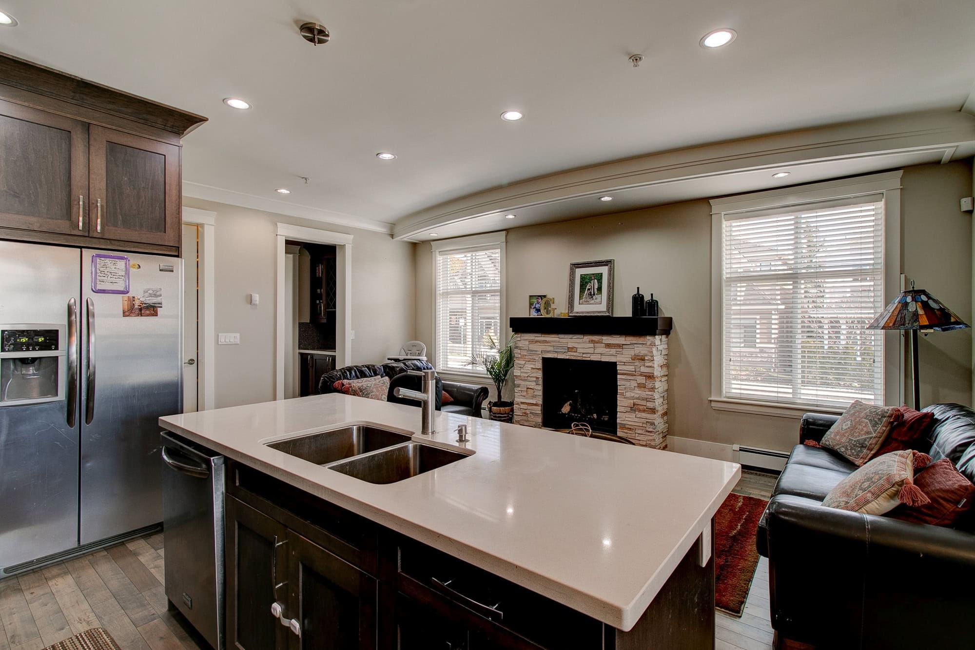 Spacious modern living room with fireplace, large windows, and open-concept kitchen featuring a kitchen island in a contemporary home.