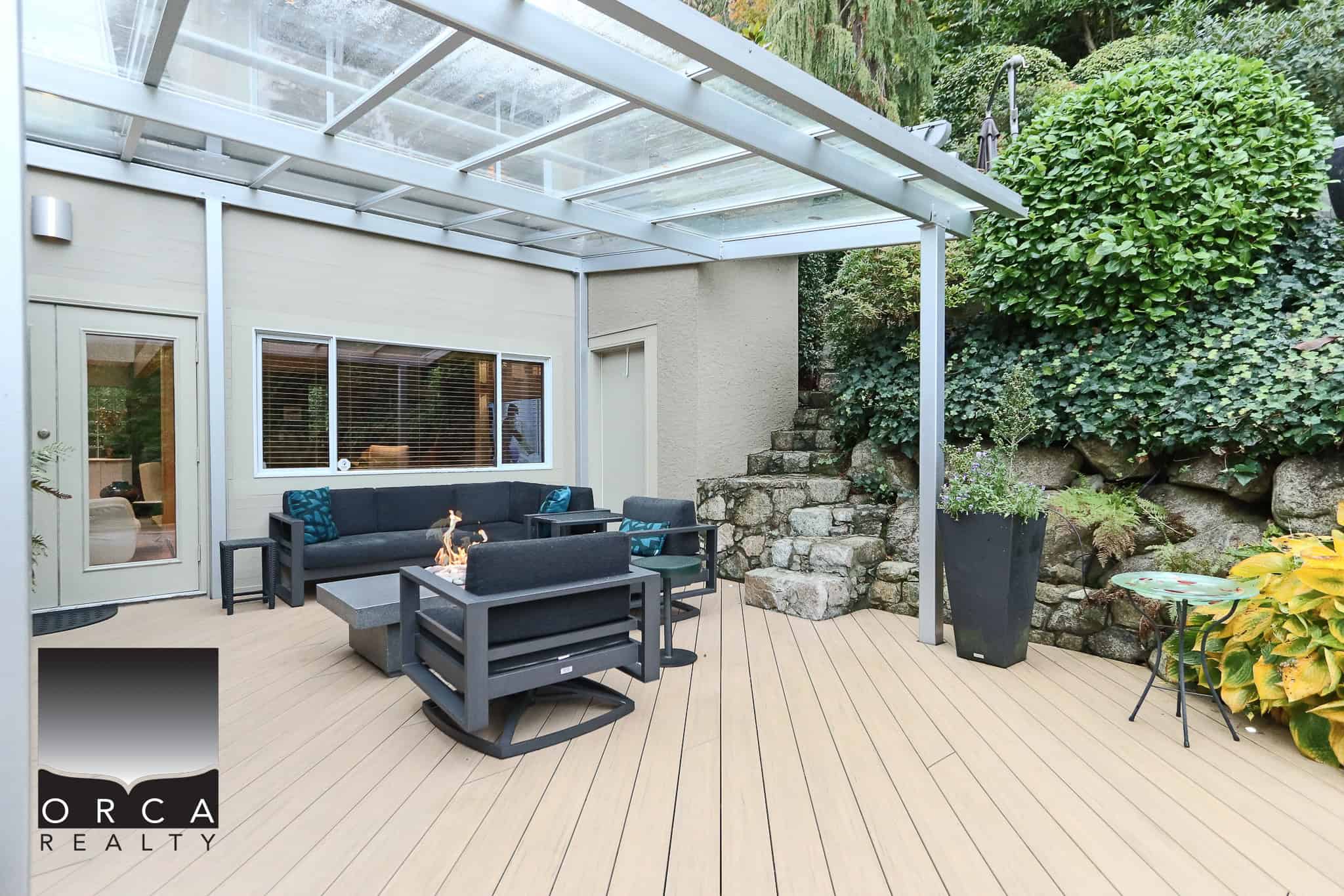 Cozy outdoor living space with firepit and comfortable seating, surrounded by lush greenery and stone accents, perfect for Vancouver Island real estate.