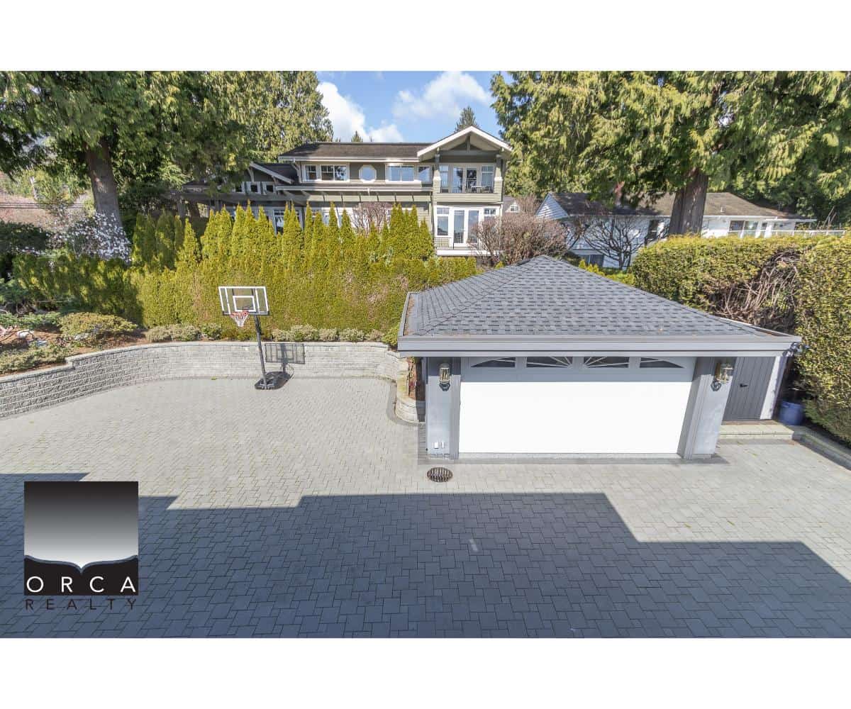 Modern residential driveway with sports court basketball hoop, landscaped backyard, and contemporary house view, showcasing Orca Realty's expertise in Vancouver Island real estate investments.