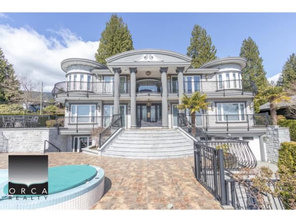 Luxury waterfront mansion with grand staircase, multiple balconies, elegant architecture, and landscaped gardens, showcasing prime real estate by Orca Realty Inc. in BC.