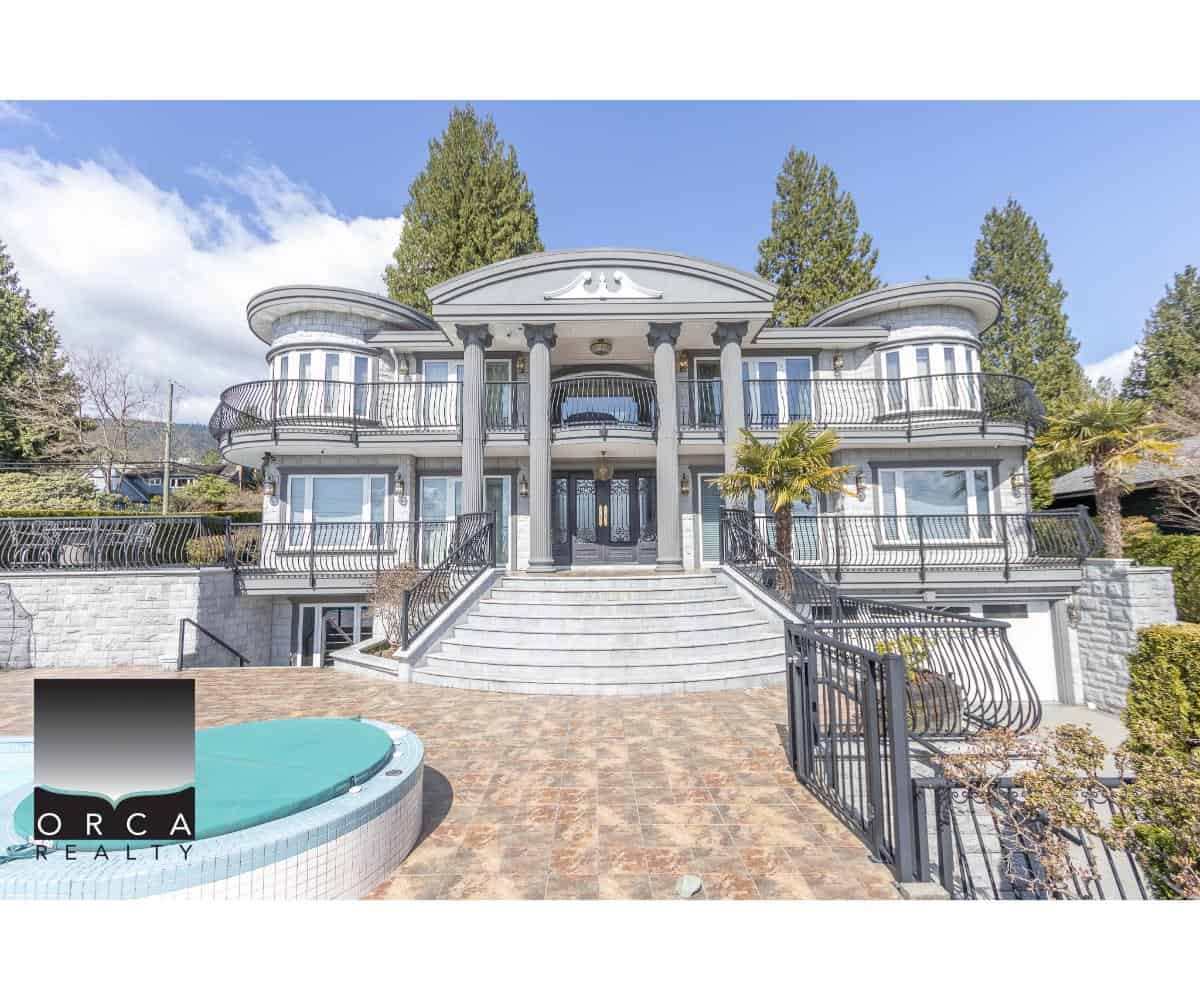 Luxury waterfront mansion with grand staircase, multiple balconies, elegant architecture, and landscaped gardens, showcasing prime real estate by Orca Realty Inc. in BC.