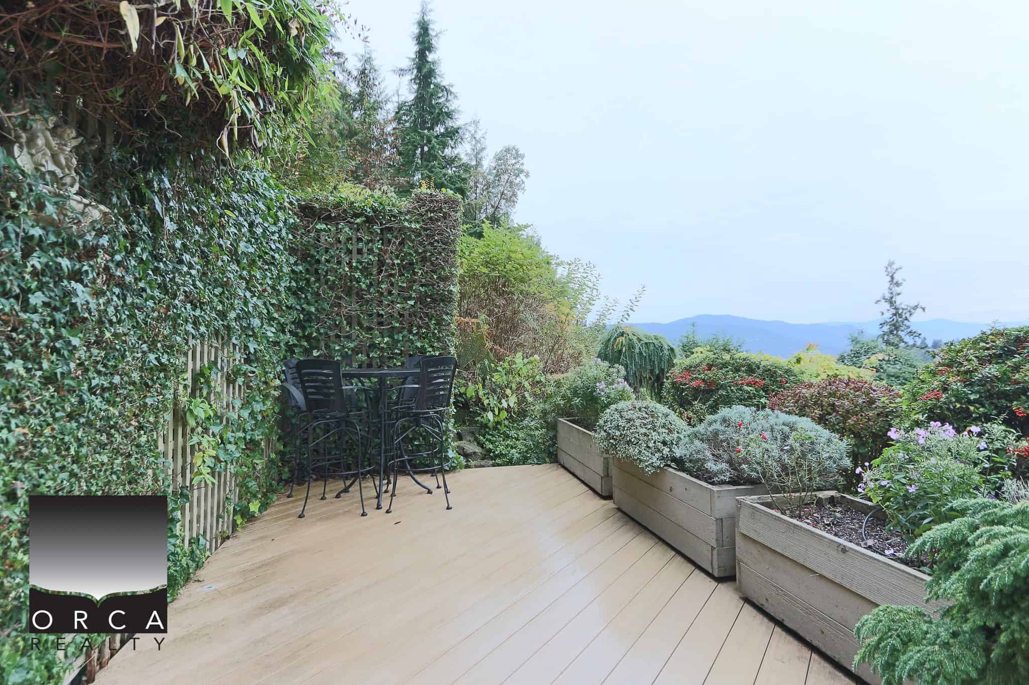 Lush garden outdoor deck with potted plants, scenic mountain views, perfect for relaxation or entertaining. Beautifully landscaped with greenery, flowers, and natural scenery.