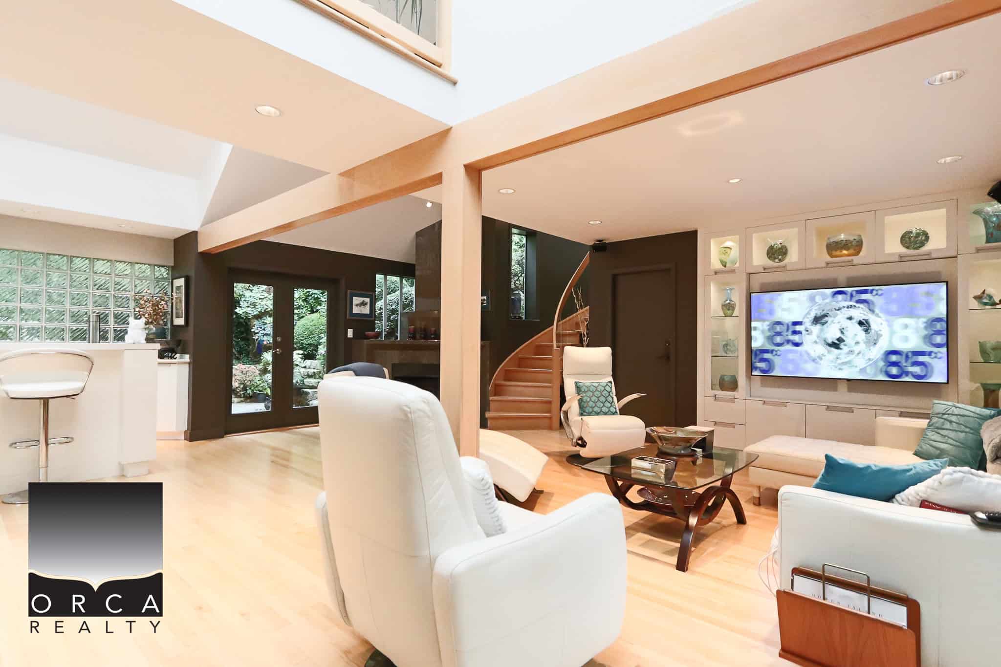Spacious contemporary living room with modern furniture, large TV, and natural light, featuring hardwood floors and a cozy fireplace – perfect for relaxed Vancouver-area home living.