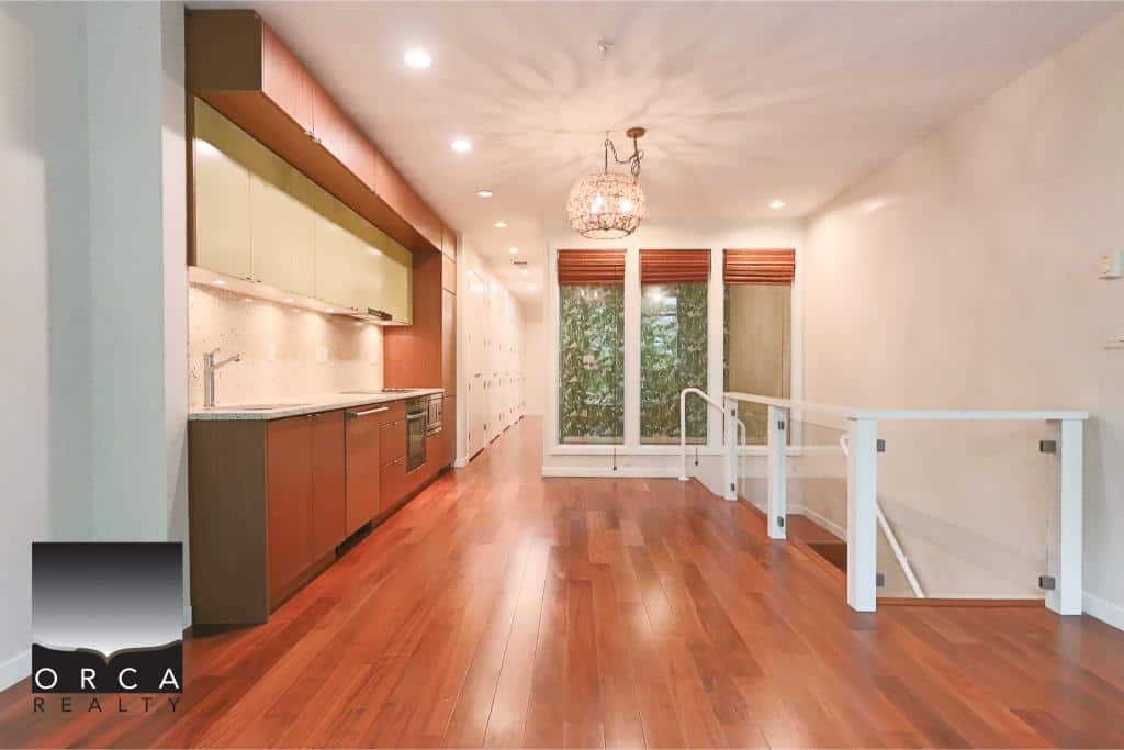 Bright open-concept living space with modern kitchen, hardwood floors, large windows, and cozy lighting, perfect for Vancouver area homes.