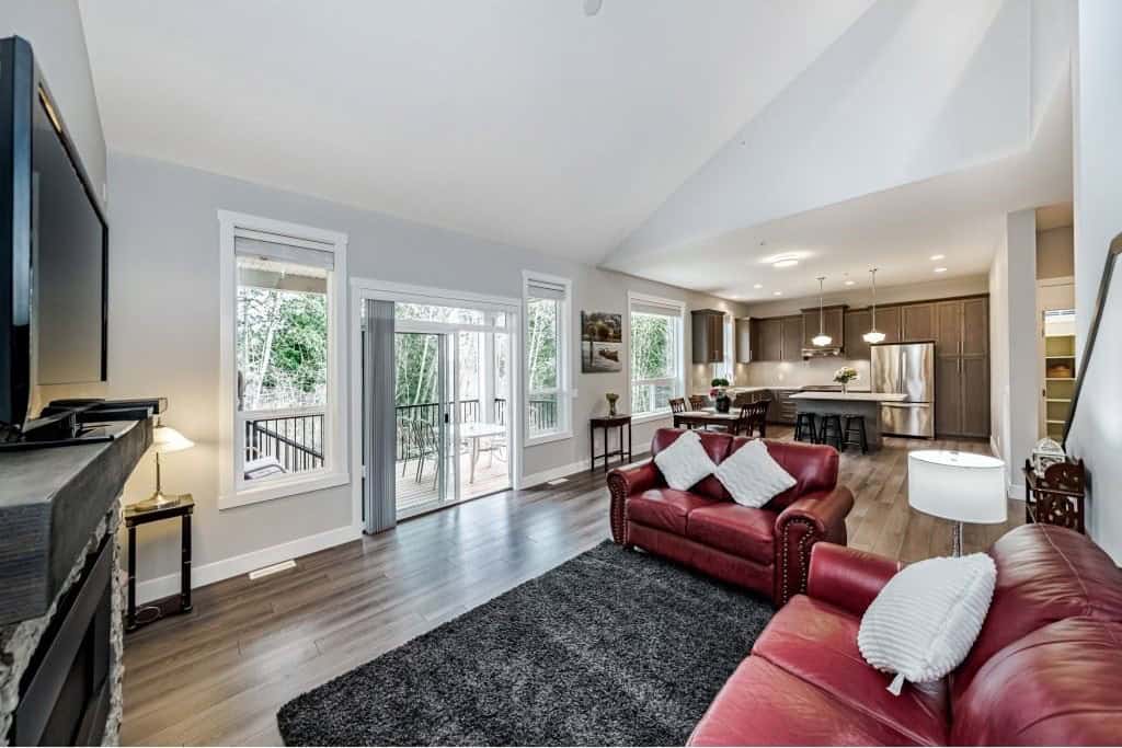 Bright open-concept living room and kitchen in a modern Vancouver home, featuring comfortable sofas, hardwood floors, large windows, and a balcony, ideal for real estate listings and property marketing.