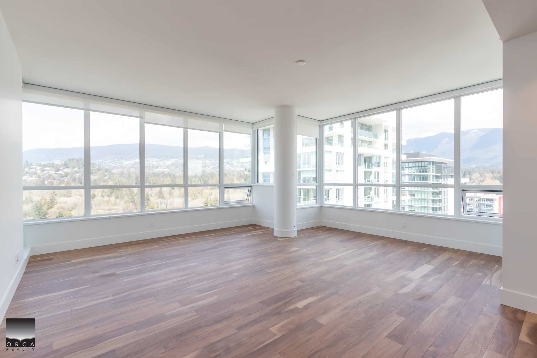 Modern high-rise apartment with floor-to-ceiling windows showcasing city and mountain views, hardwood floors, open-concept living space, ideal for urban living in Vancouver, BC.