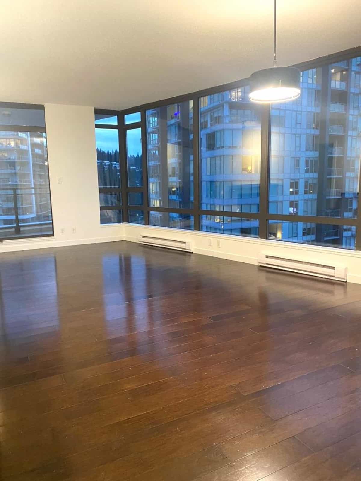 Bright modern condo living space with floor-to-ceiling windows, showcasing stunning city views, polished hardwood floors, and ample natural light, ideal for urban living in Vancouver.