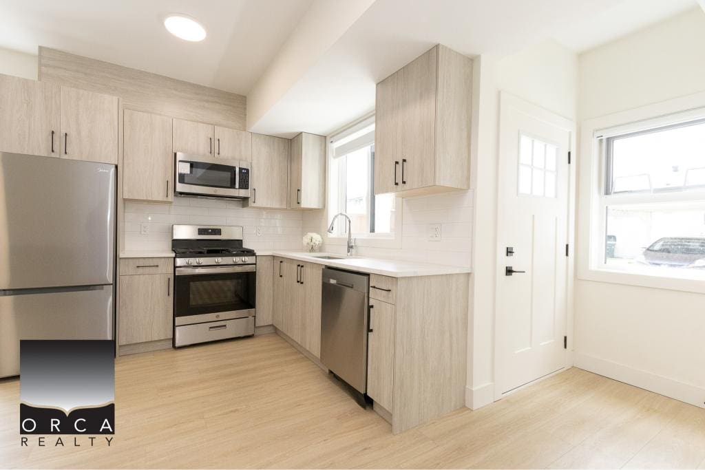Modern kitchen with stainless steel appliances, white cabinetry, and natural light, perfect for Vancouver homebuyers seeking stylish, functional, and contemporary real estate in BC.