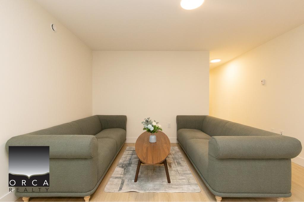 Modern living room featuring two comfortable green sofas, a central wooden coffee table, and minimalist decor in a spacious, well-lit interior.