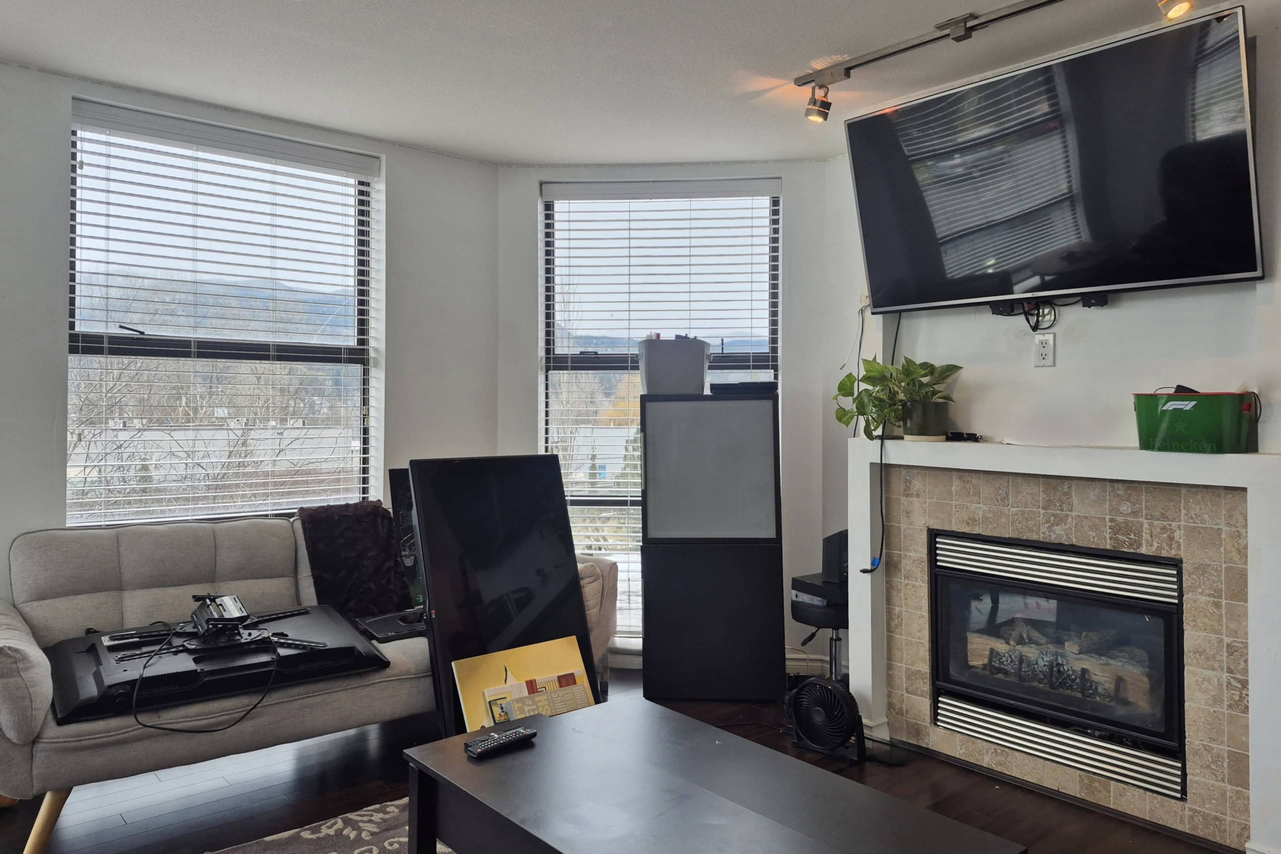 Bright living room with large windows, modern fireplace, and wall-mounted TV, perfect for family gatherings and relaxation in a downtown Orca Realty Inc. property.