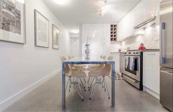 Modern kitchen with sleek white cabinetry, stainless steel appliances, and a stylish dining area featuring a blue-topped table and beige chairs, perfect for Vancouver city living.