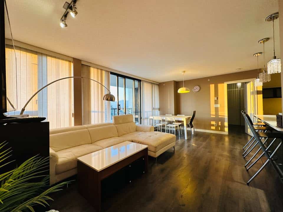 Modern ocean-view living room in Vancouver apartment, featuring spacious seating area, large windows with natural light, contemporary dining table, and stylish decor for comfortable living.