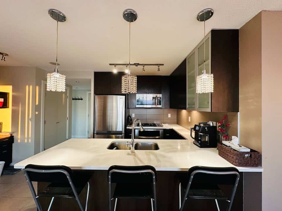 Modern kitchen with stainless steel appliances and contemporary lighting fixtures.