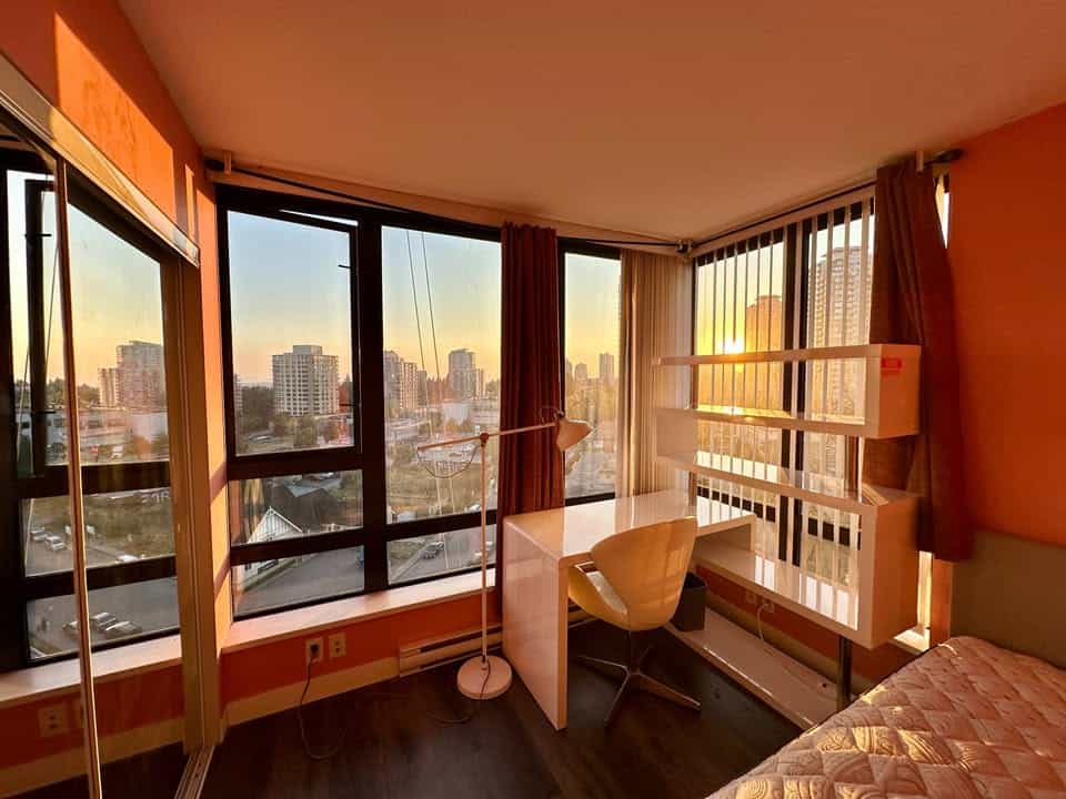 Panoramic city view from a high-rise apartment window in Vancouver, BC, showcasing modern city living and scenic sunsets, ideal for real estate and rental opportunities.