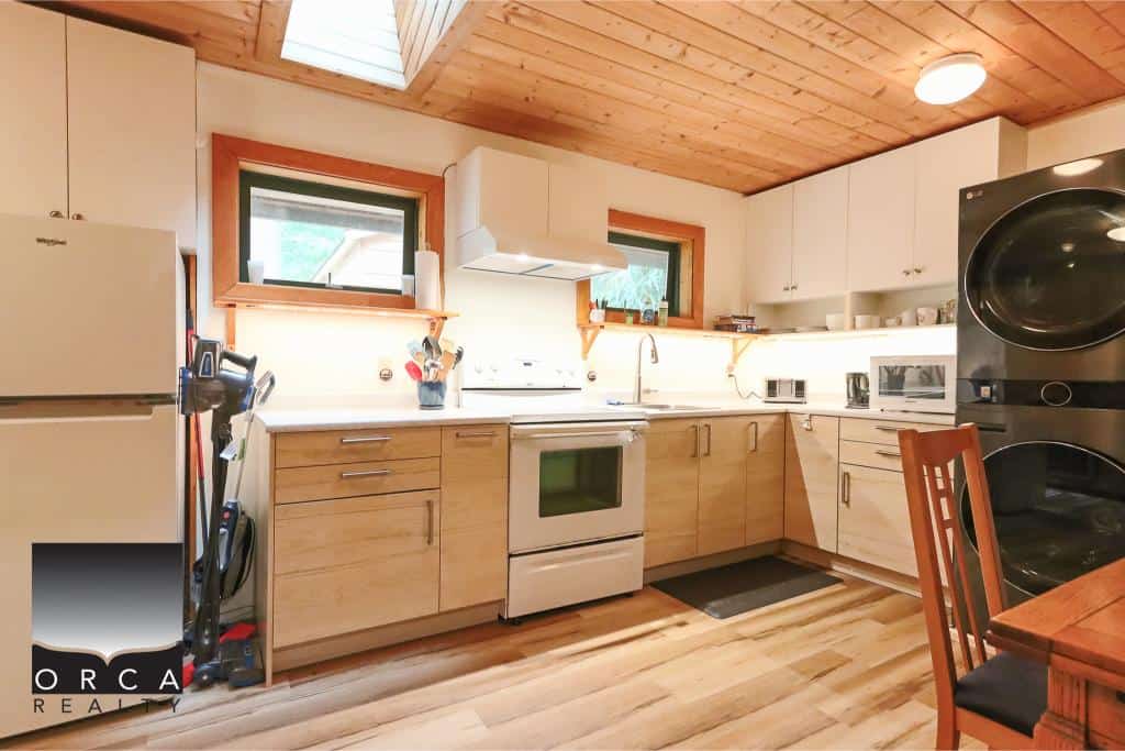 Modern kitchen with wooden cabinets, stainless steel appliances, and natural light for cozy living, ideal for those seeking homes with a warm, inviting atmosphere and functional space.