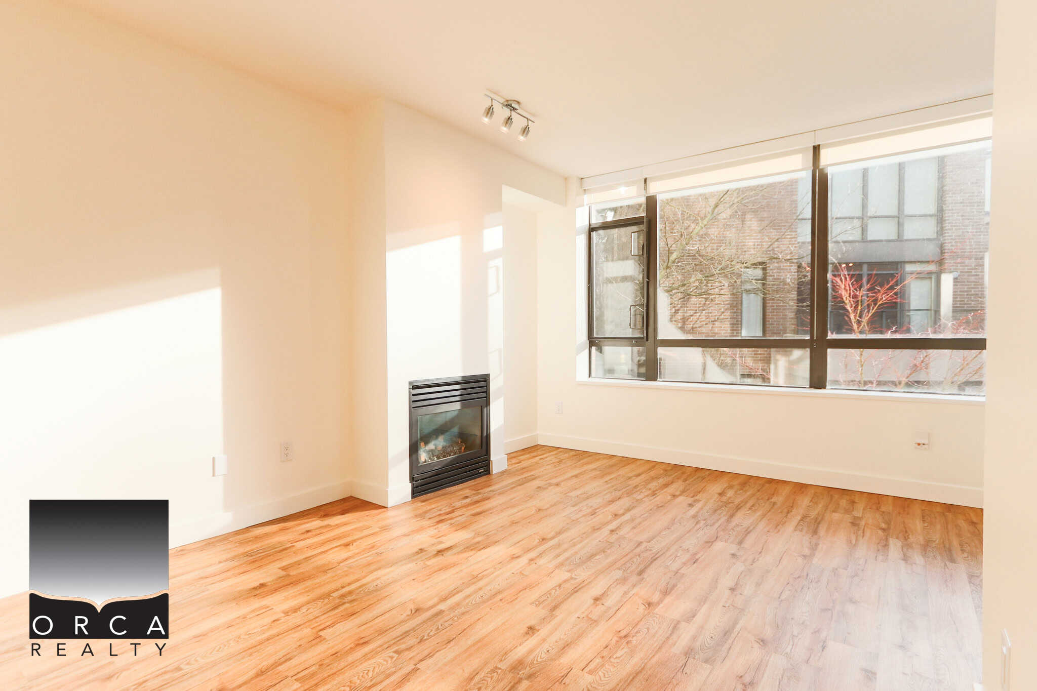 Bright, spacious living room with large windows and hardwood floors in North Vancouver. Perfect for relaxing or entertaining, showcasing a cozy fireplace and natural light.