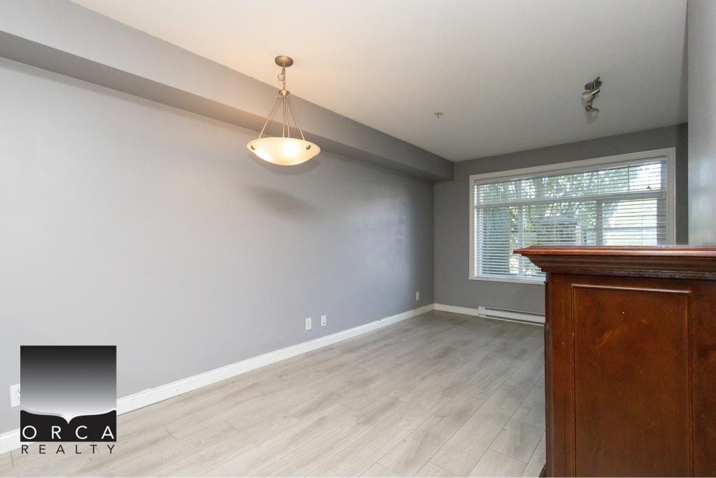 Bright living room with large window, neutral grey walls, and modern light fixture, perfect for Vancouver area homebuyers and real estate listings by Orca Realty Inc.
