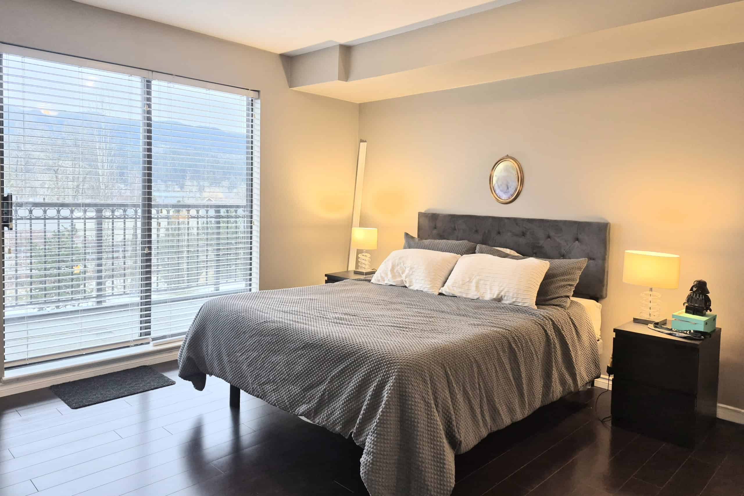 Bright modern bedroom with large windows, mountain view, and stylish decor; ideal for Vancouver real estate listings or property marketing.