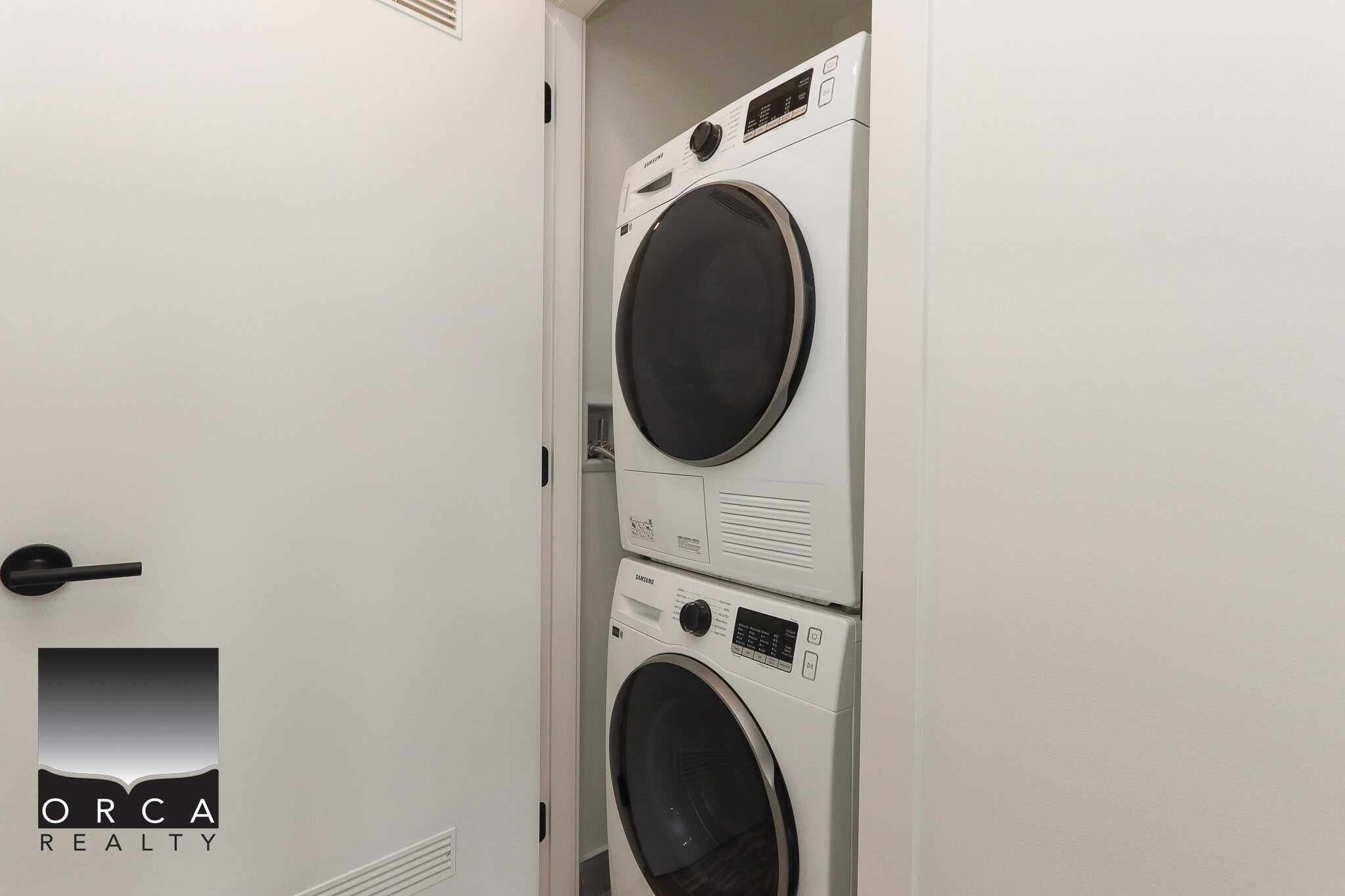 Stacked white washer and dryer in a laundry closet. Compact and modern appliances perfect for condo living. Conveniently located for easy laundry access. Ideal for real estate listings showcasing property amenities.