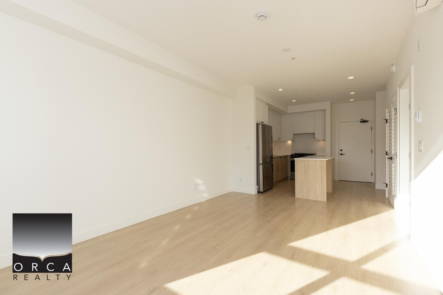 Bright open-concept living space with modern kitchen, white cabinetry, and natural light, perfect for Vancouver Island real estate buyers interested in new condos and homes.