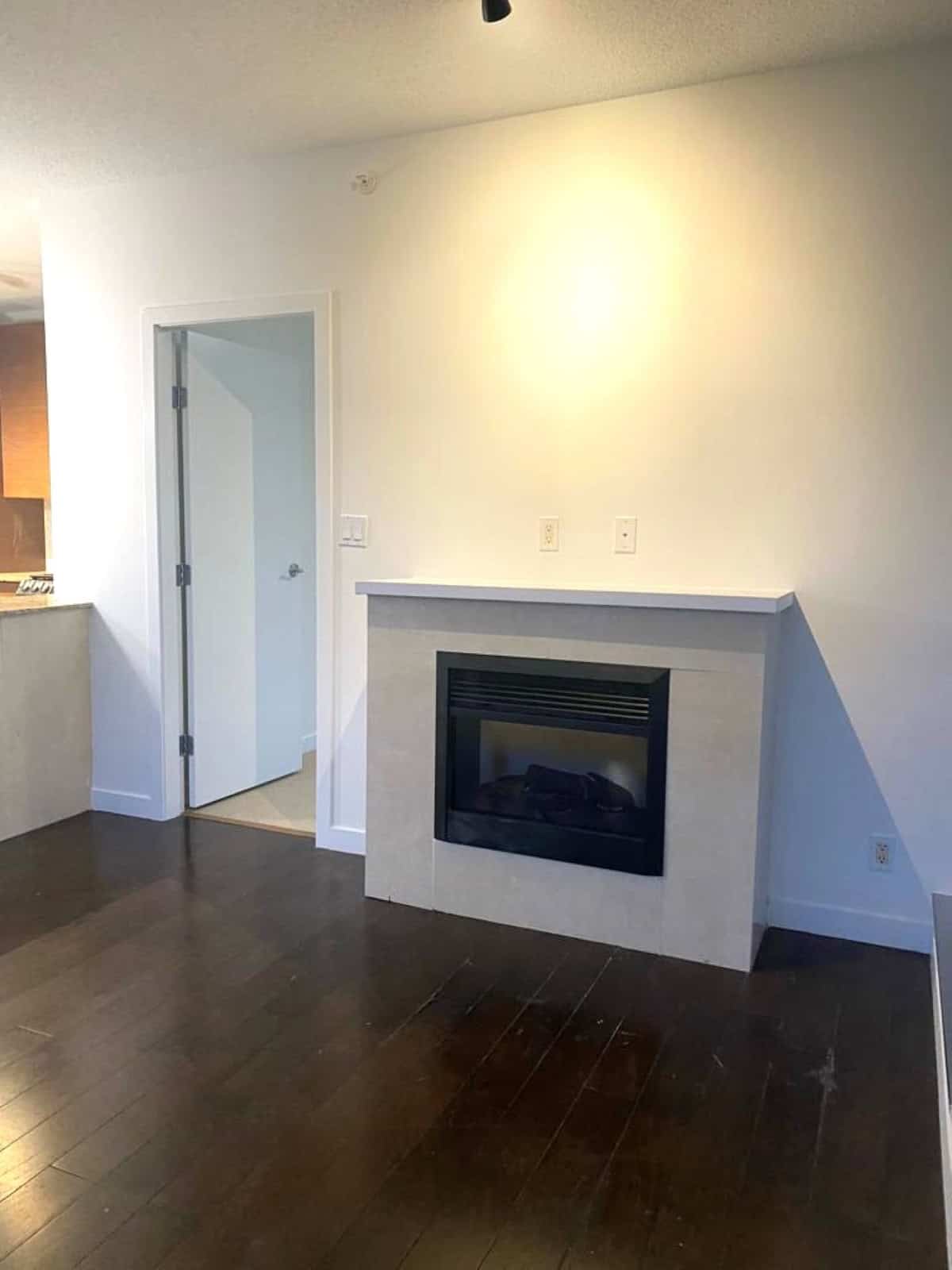 Cozy living room with modern fireplace, hardwood flooring, and white walls, offering a warm and inviting atmosphere for homebuyers in Vancouver, BC.