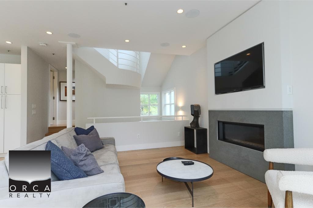 Modern living room interior with fireplace, flat-screen TV, neutral furniture, hardwood floors, and natural light, showcasing a stylish and comfortable home for real estate in Canada.