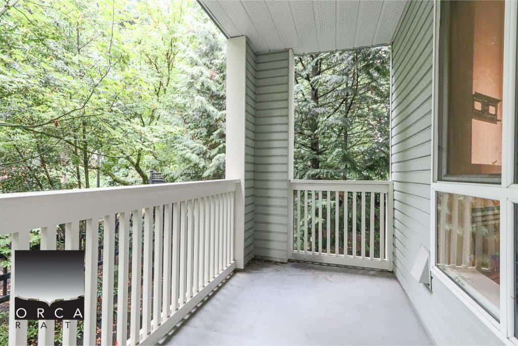 Bright balcony with white railing and lush green trees, perfect for outdoor relaxing and enjoying nature in your British Columbia home.