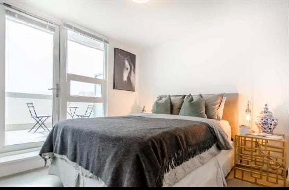 Modern bedroom with large windows, cozy bedding, and stylish decor, ideal for Vancouver real estate listings.