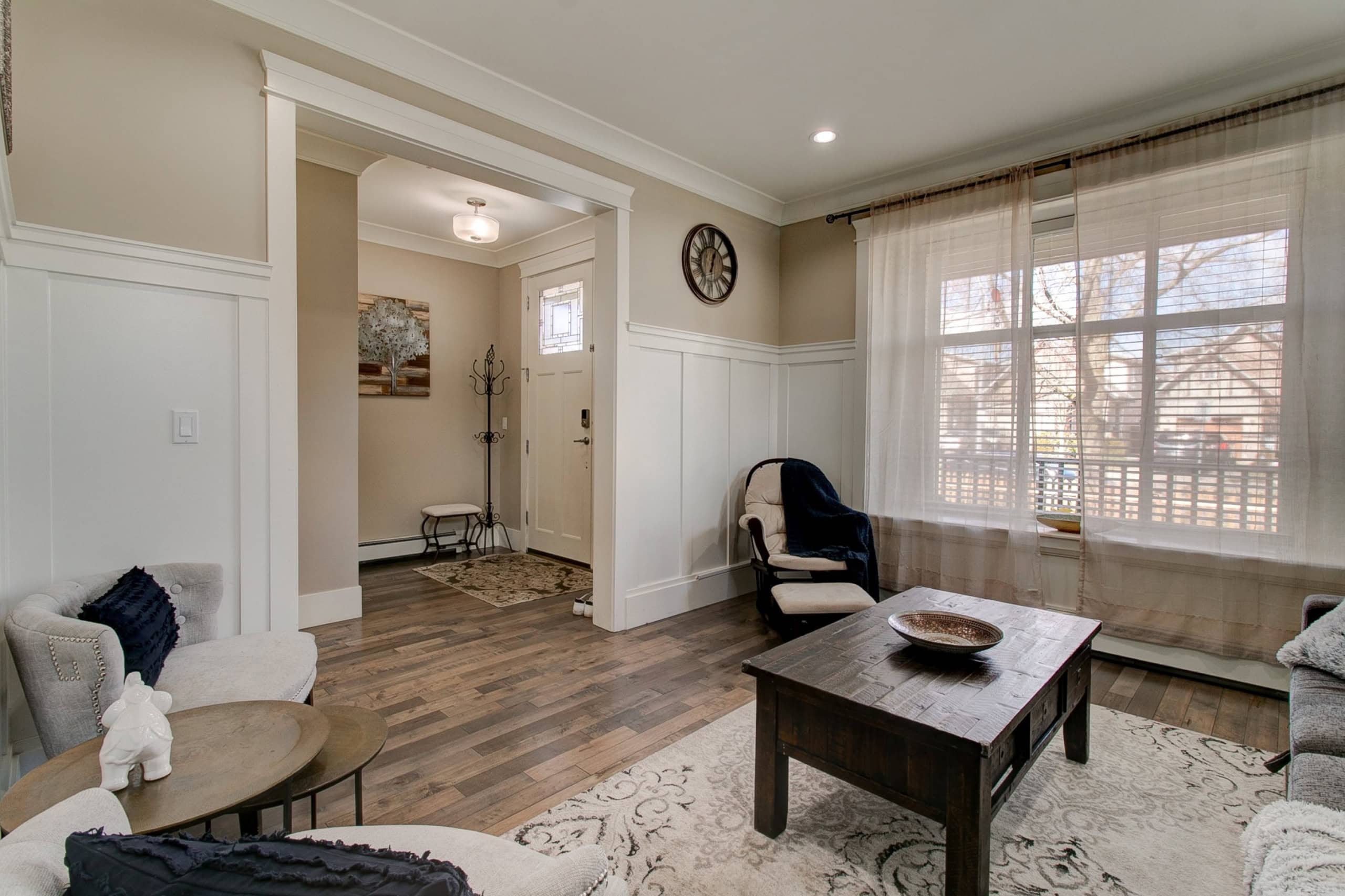 Bright and inviting living room with large windows, neutral decor, and hardwood flooring, showcasing a cozy space perfect for family gatherings and relaxing at home.