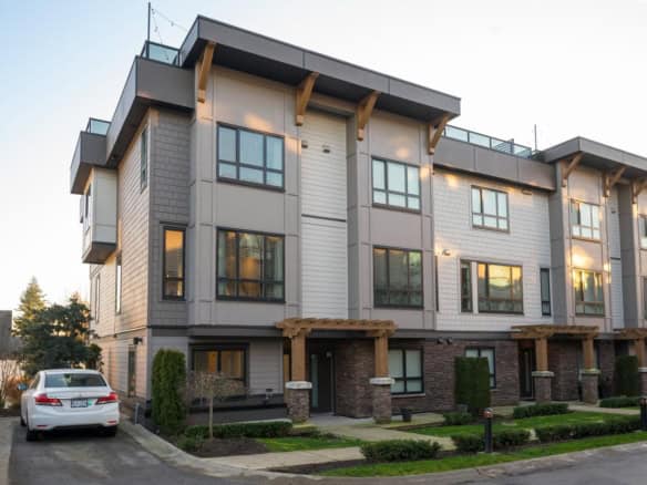 Contemporary multi-family residential building showcasing modern architecture with large windows, wood accents, and landscaped surroundings, ideal for Vancouver real estate investments.