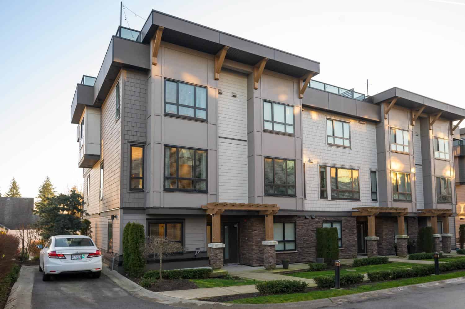 Contemporary multi-family residential building showcasing modern architecture with large windows, wood accents, and landscaped surroundings, ideal for Vancouver real estate investments.