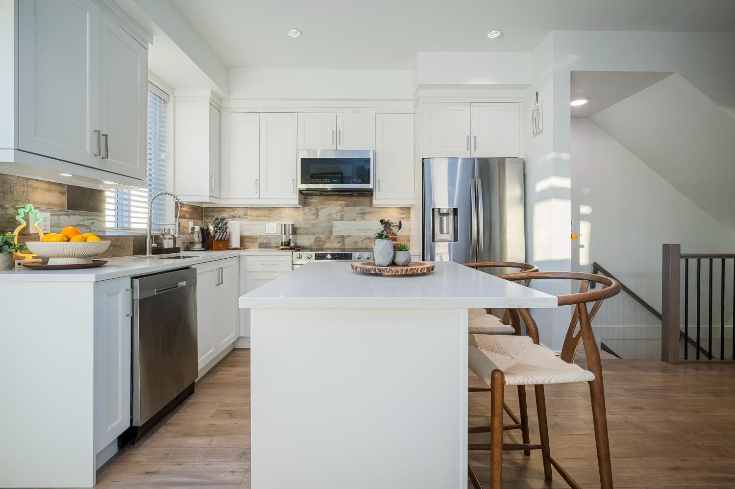 Bright modern chef's kitchen with white cabinetry, stainless steel appliances, and a large island featuring seating, perfect for family updates and entertaining in a contemporary home.
