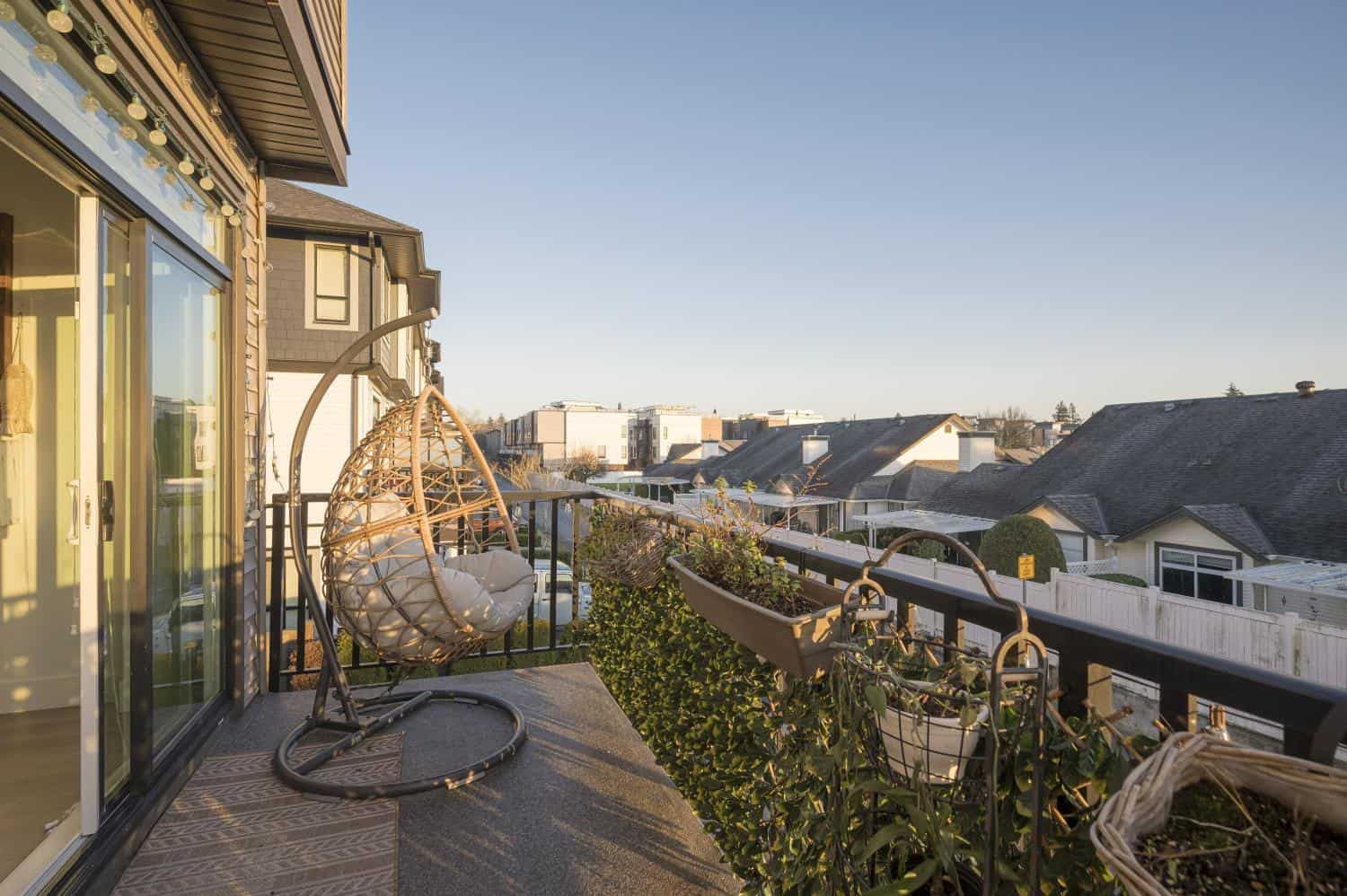 Cozy balcony with modern hanging egg chair, outdoor plants, and cityscape view showcasing Vancouver-style residential homes, perfect for Vancouver real estate, property investment, and realty services.