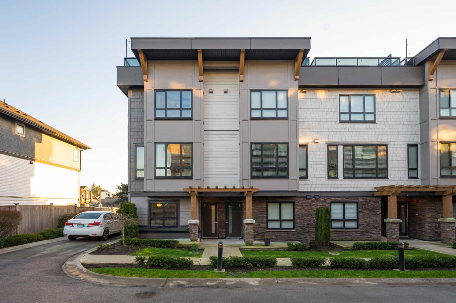 Contemporary multi-family residential building with modern architecture, large windows, and landscaped front yard, available through Orca Realty Inc. in Vancouver, BC.