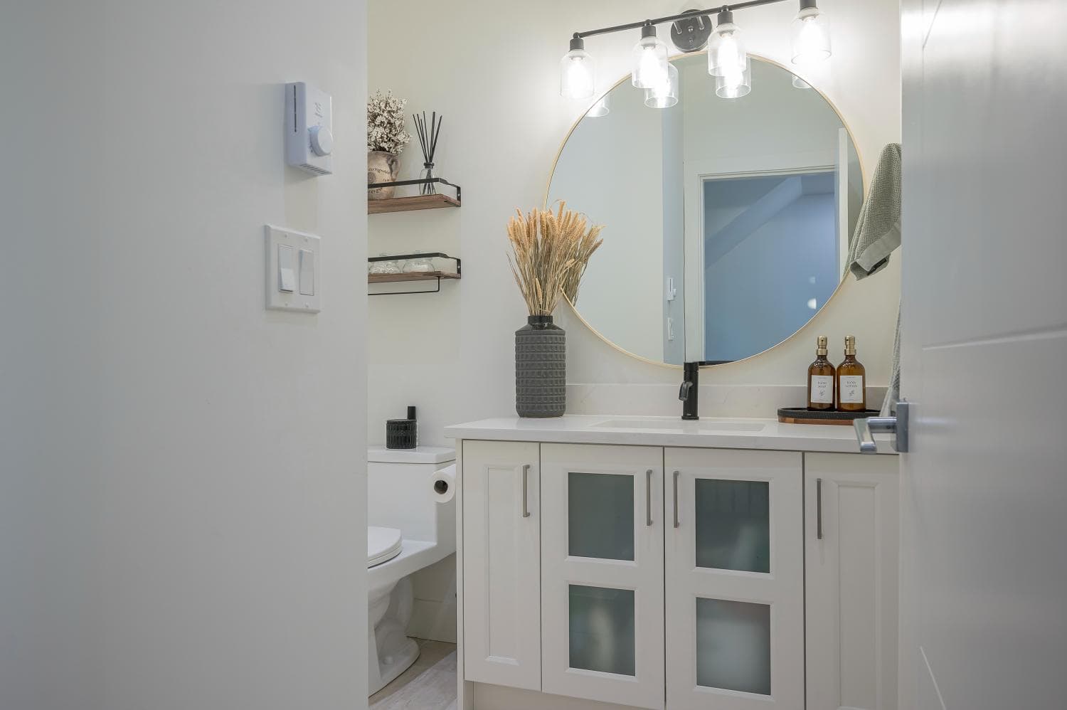 Bright modern bathroom interior with white cabinetry, round mirror, and stylish decor, perfect for Vancouver real estate listings and showcasing premier property features.
