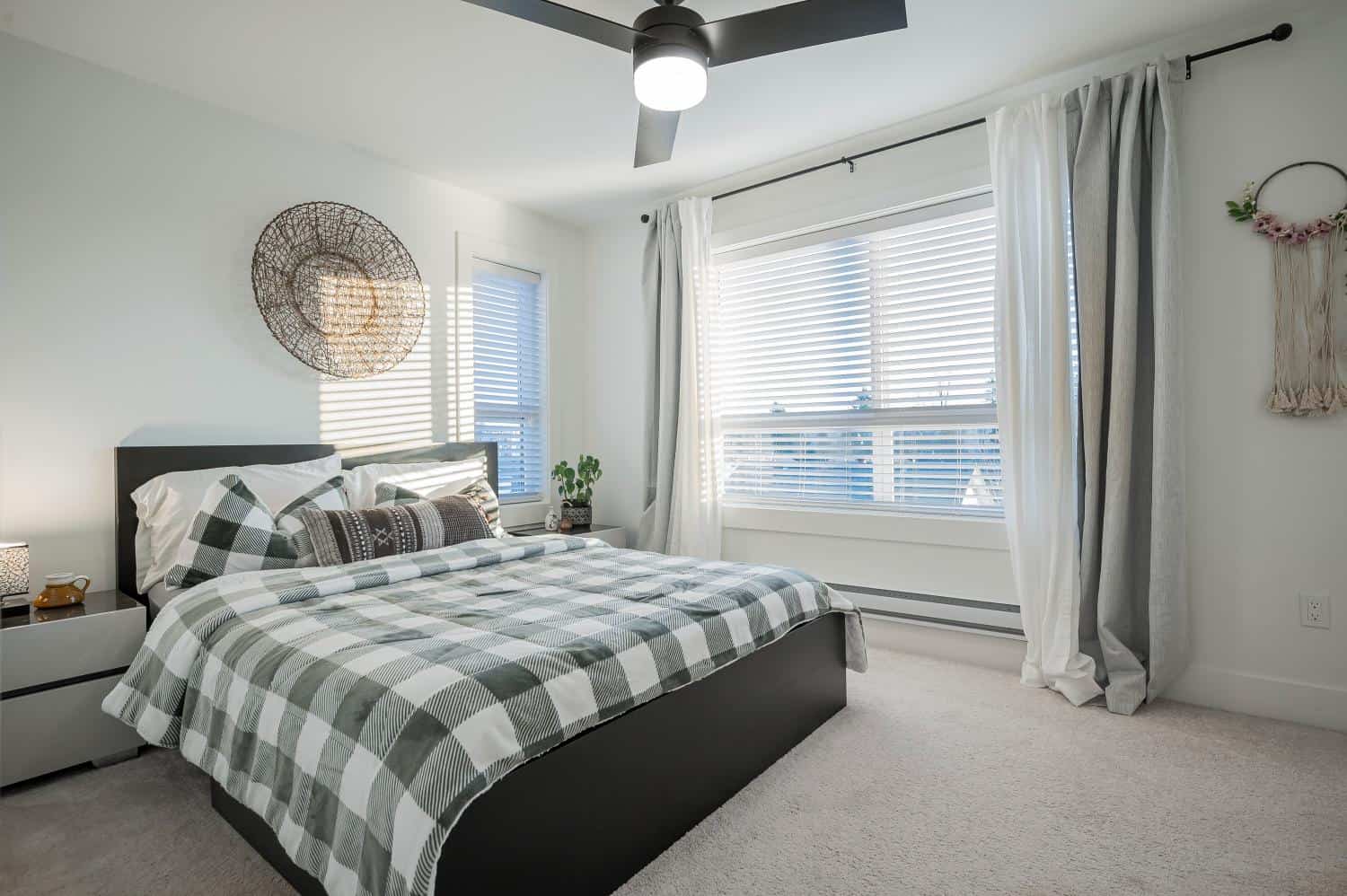 Cozy modern bedroom with large windows, white curtains, and minimalist decor, perfect for Vancouver homebuyers or real estate investors seeking comfortable living spaces.