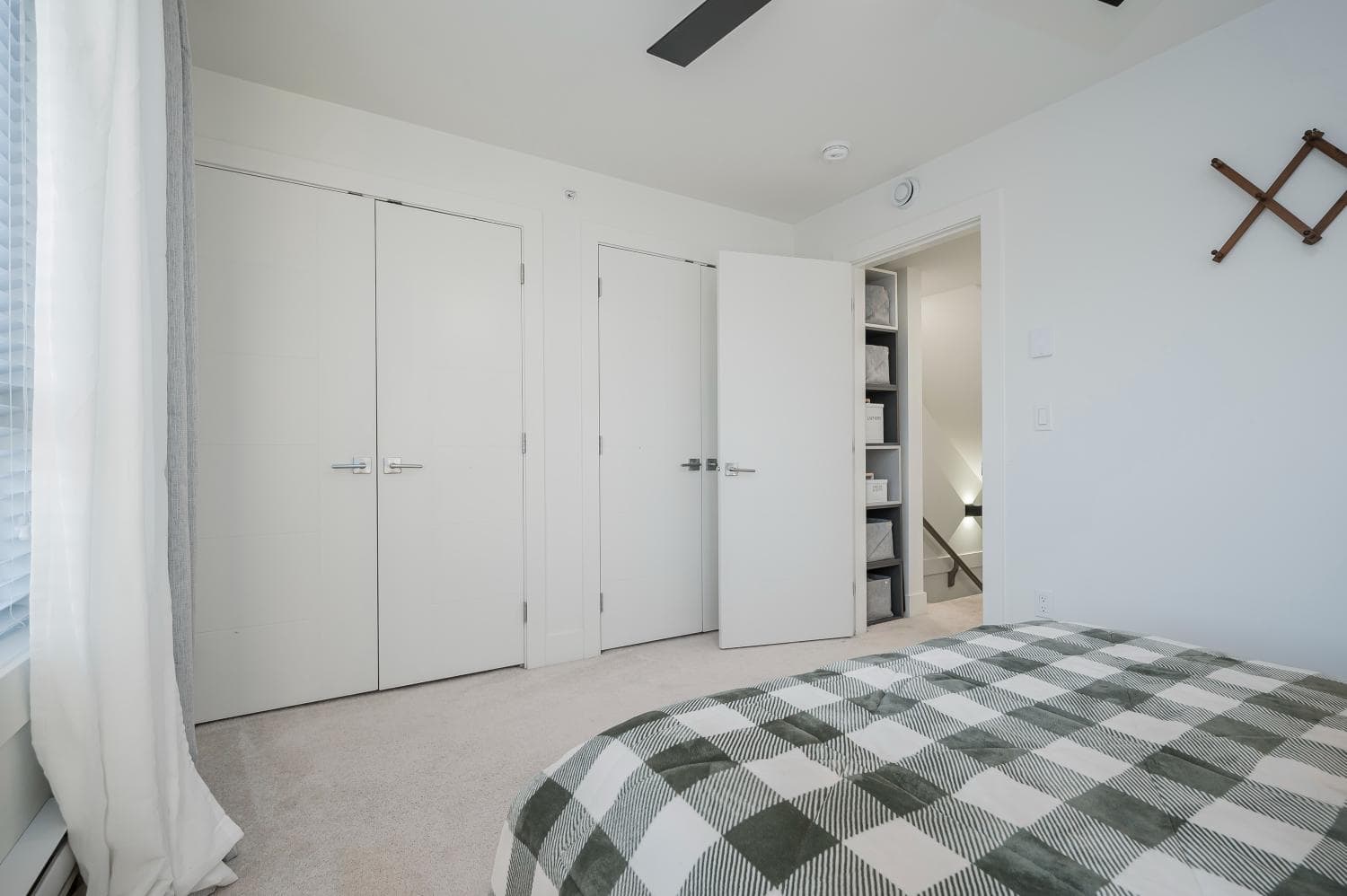 Bright modern bedroom with white closets, minimalist decor, and natural light from large window, showcasing the quality and style of Orca Realty Inc. property listings in British Columbia.