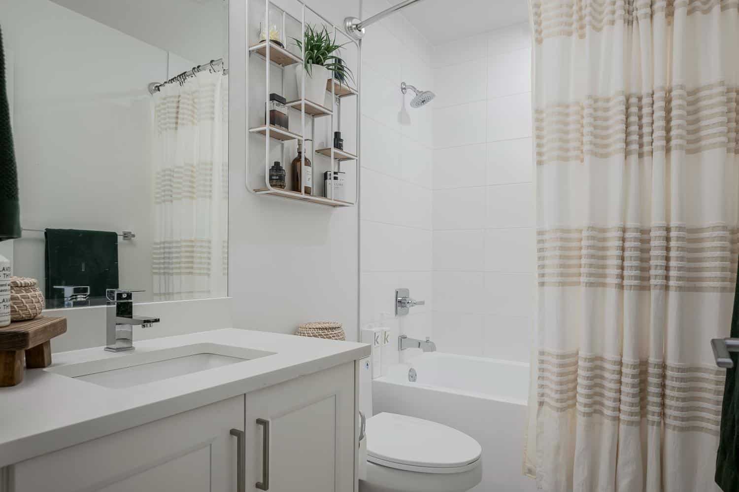 Modern bathroom with white tiles, shower, bathtub, and minimalist decor, featuring a stylish vanity and storage shelves, ideal for comfortable living in Vancouver.