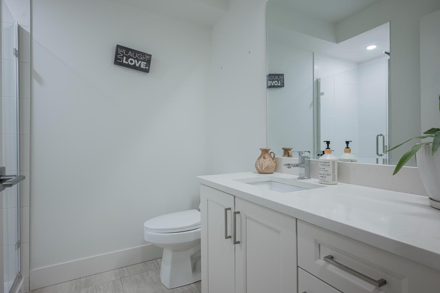 Modern bathroom with sleek white cabinetry, contemporary fixtures, and decorative accents, showcasing the clean and inviting design of Orca Realty Inc. listings.