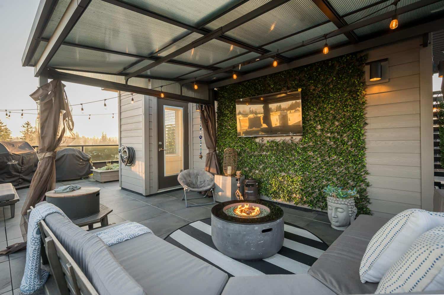Modern rooftop terrace with outdoor seating, fire pit, and lush wall greenery featuring in Vancouver real estate listings.