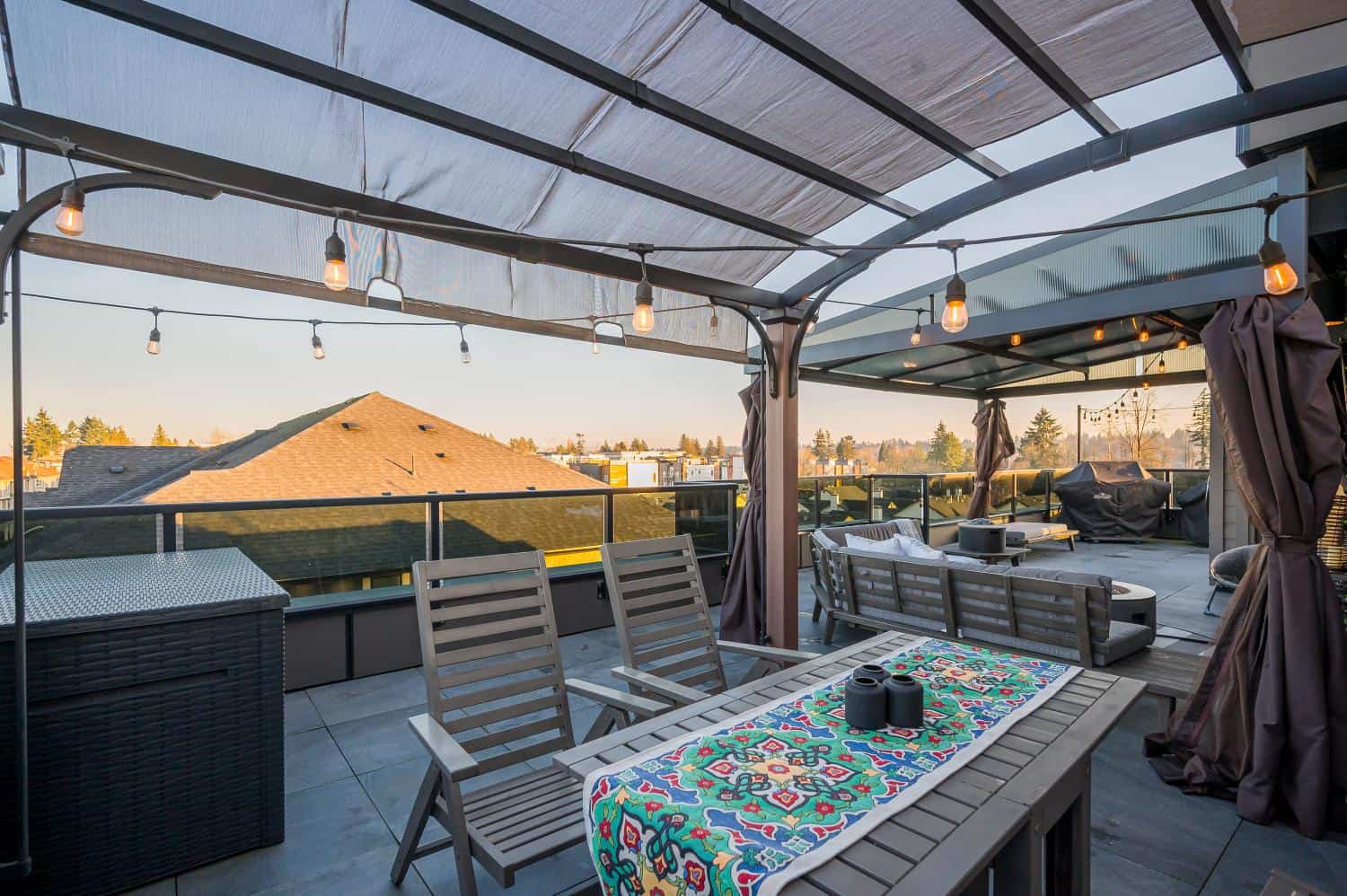 Spacious rooftop patio with outdoor dining, seating area, string lights, and city views, perfect for relaxing and entertaining in Vancouver's desirable real estate market.