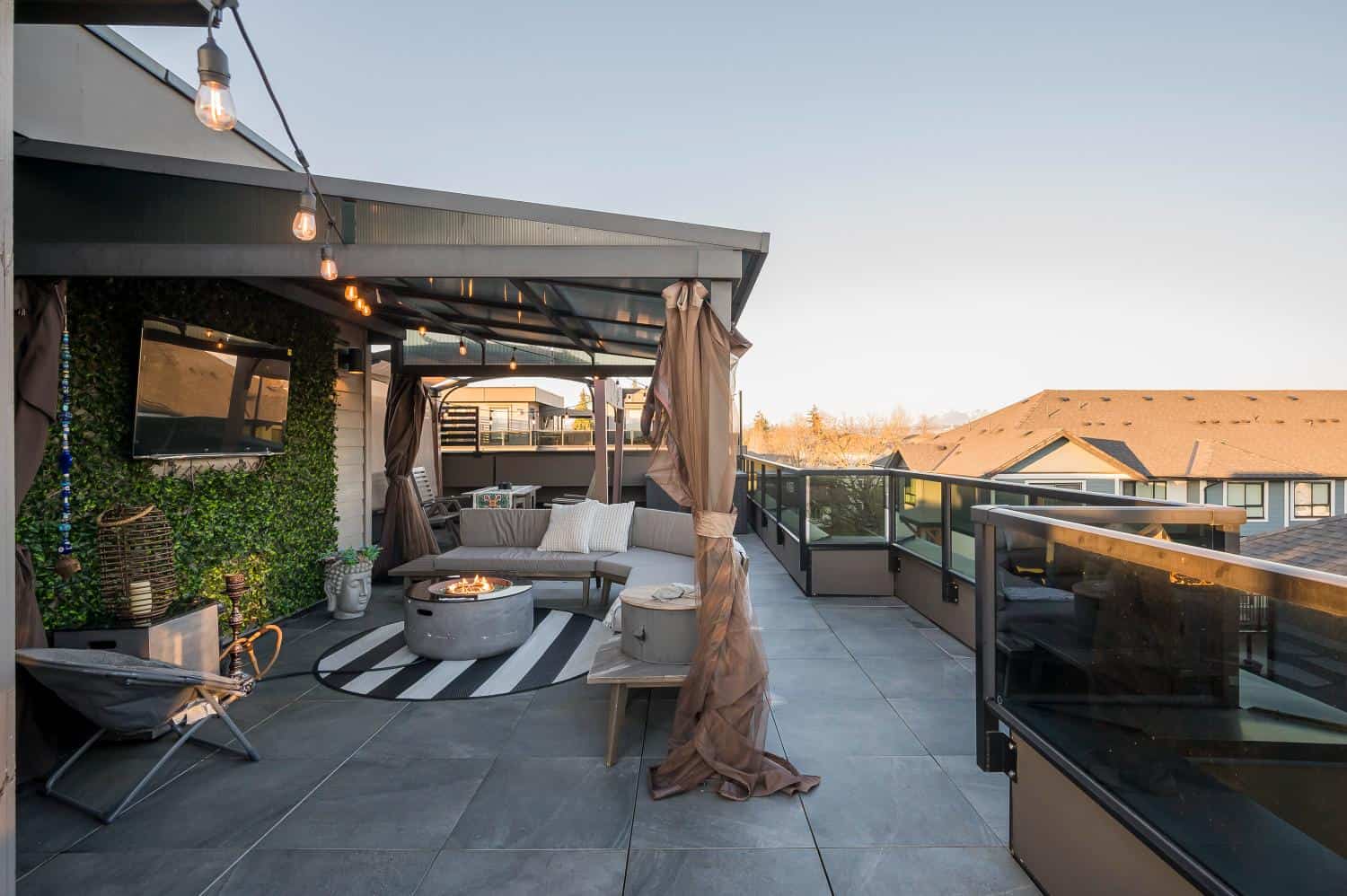 Balcony outdoor living space with cozy seating, fire pit, string lights, and modern decor, perfect for entertaining and enjoying scenic views.