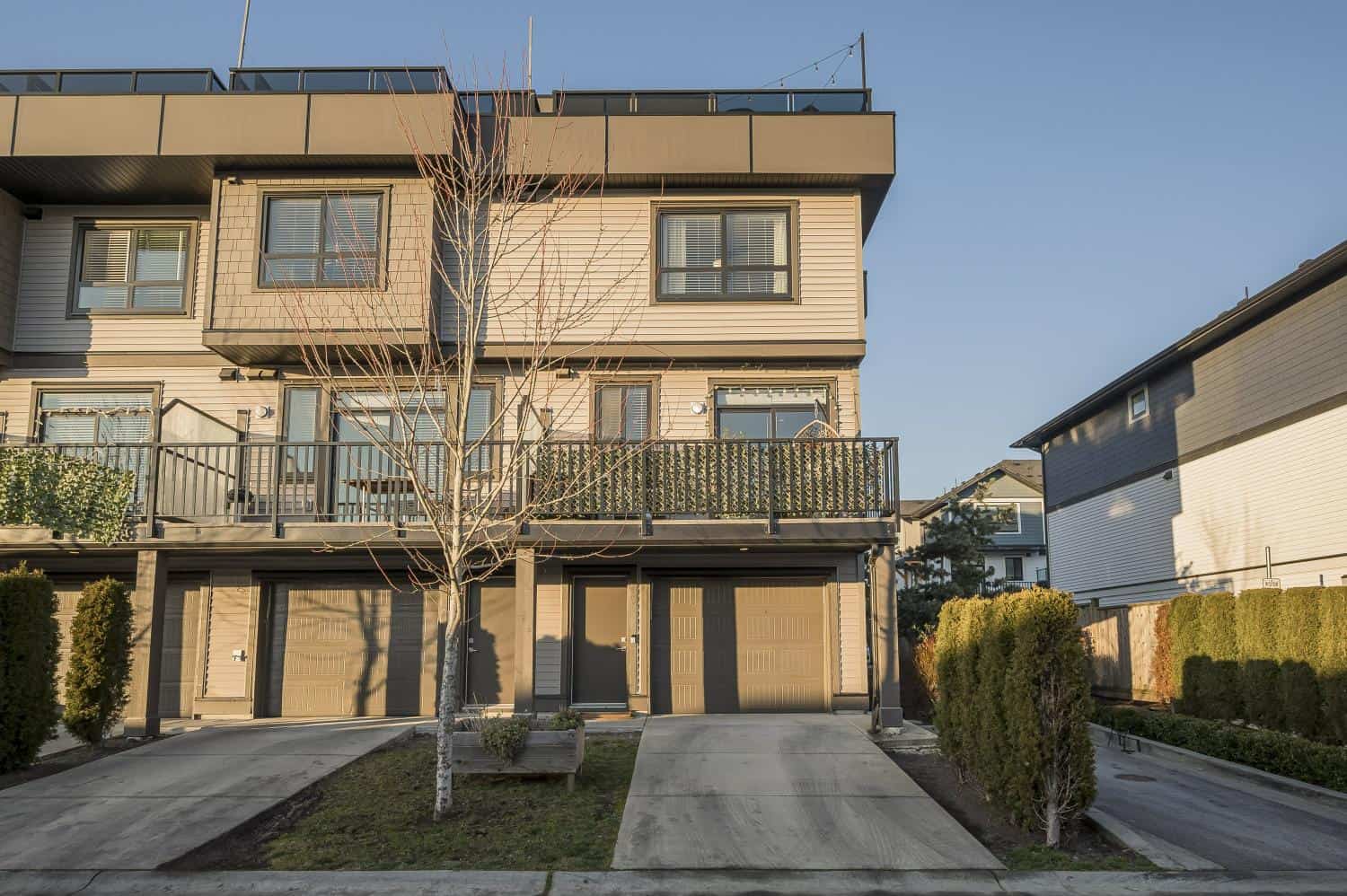 Modern townhouse with garage parking, featuring sleek exterior design, private balconies, and well-maintained landscaping, ideal for Vancouver real estate investment.